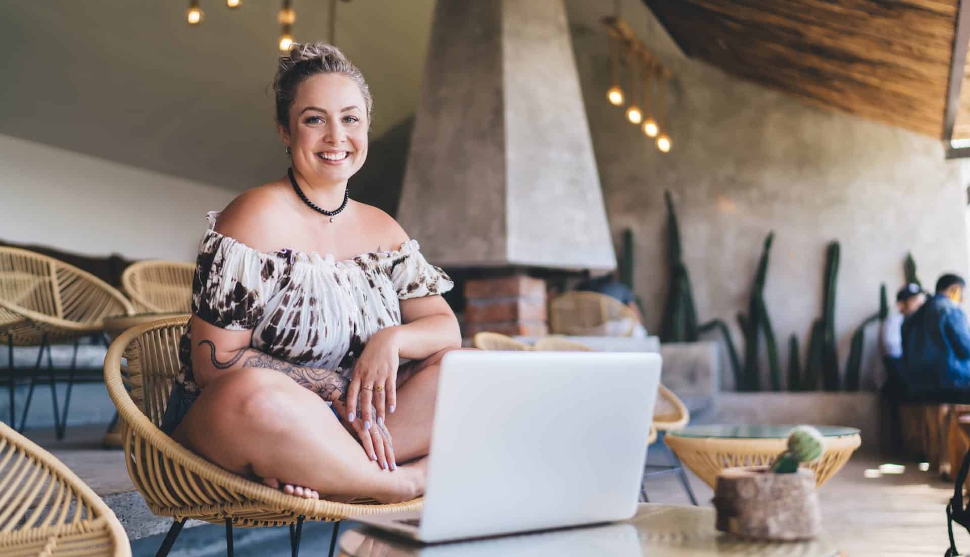 Femme travaillant sur un ordinateur portable dans un café moderne, symbolisant l'agence web IA.